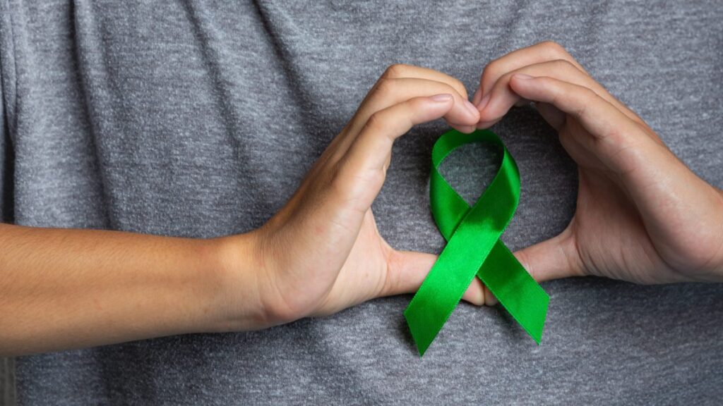 world mental health day man s hand showing heart shaped around green ribbon 1200x675 1